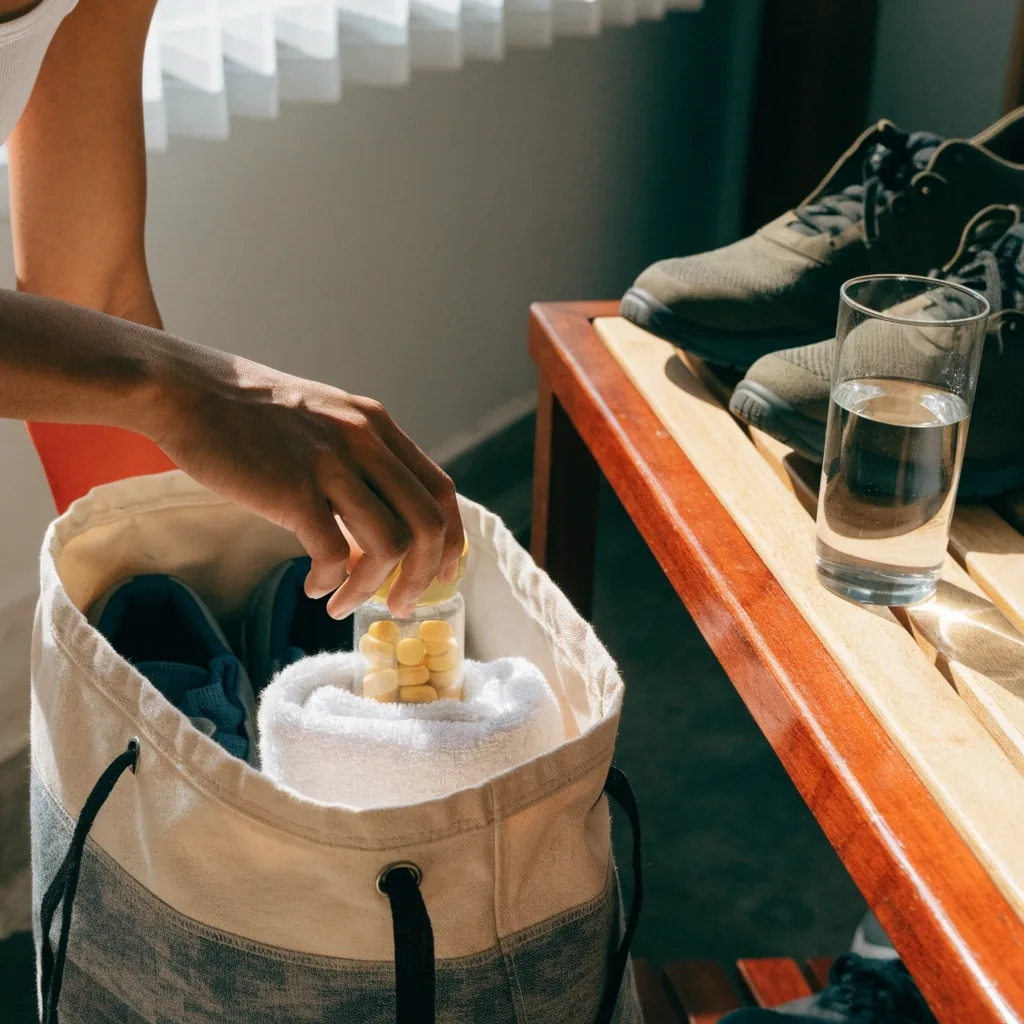 Plain unbranded training shoes and a towel on linen beside a glass of water