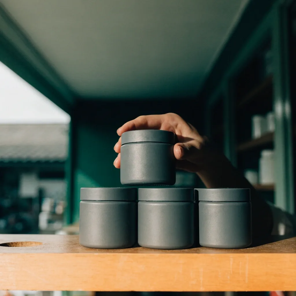 Four unmarked supplement jars spaced along a timber ledge under soft light